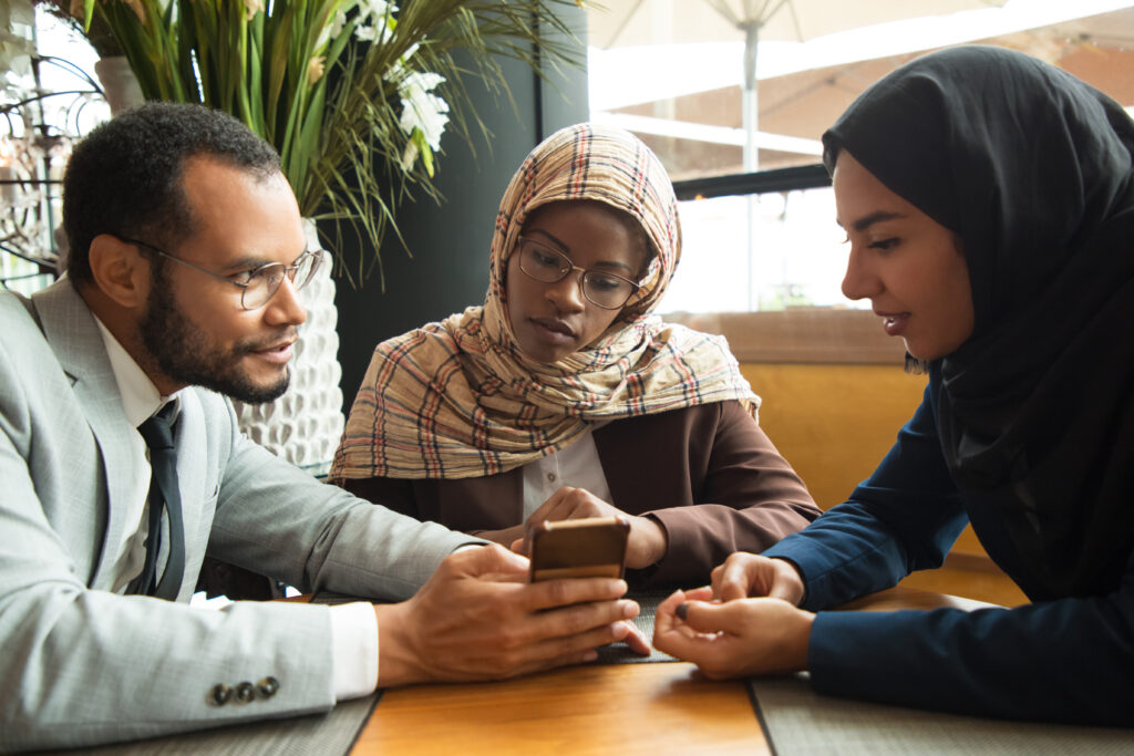 excited diverse coworkers watching content on smartphone