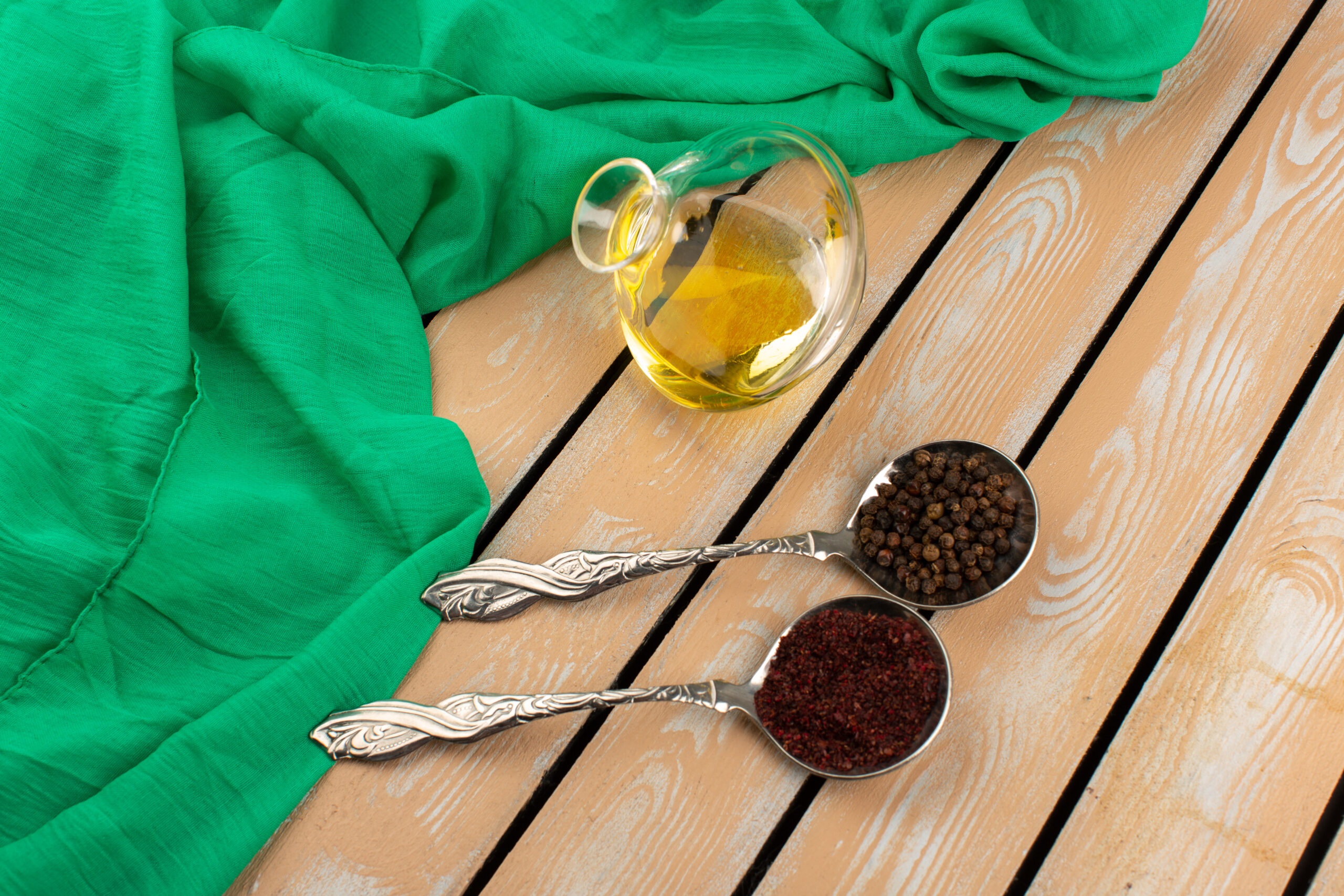 top view peppers inside silver spoons along with olive oil brown wooden background
